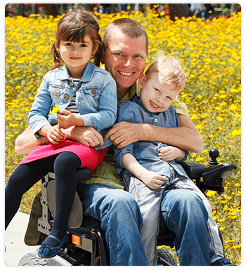 man in wheelchair holding two kids